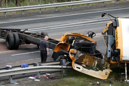 A police investigator looks at the wreckage of a school bus on Interstate 80 following an accident with a dump truck in Mount Olive Township, New Jersey, U.S., May 17, 2018. REUTERS/Mike Segar