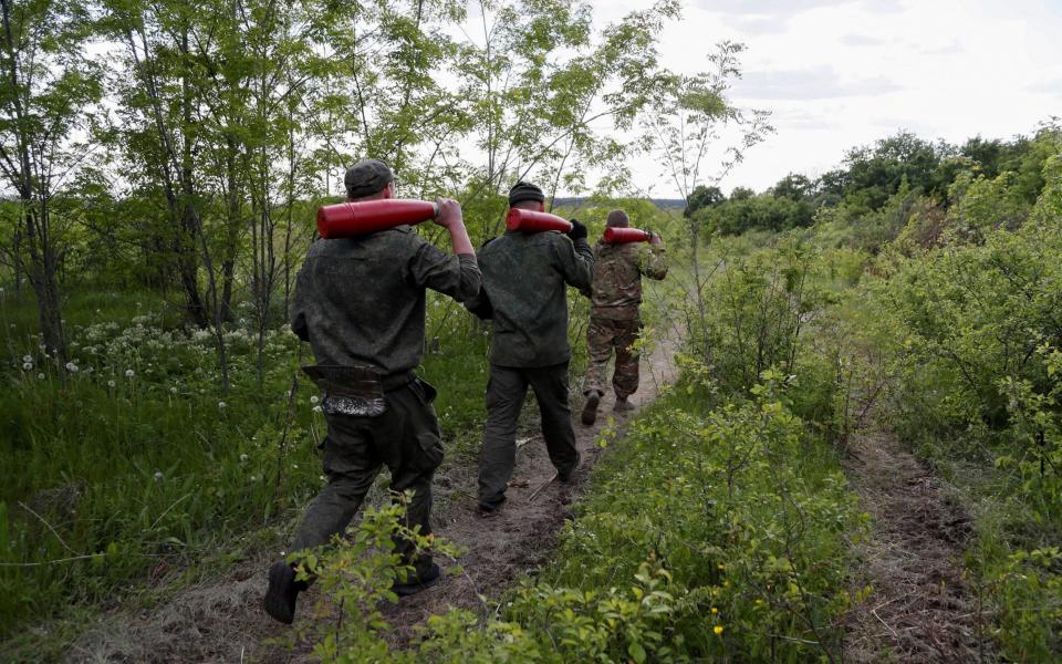 Service members of pro-Russian troops carry leaflet shells at their combat positions in the Luhansk region, Ukraine May 24