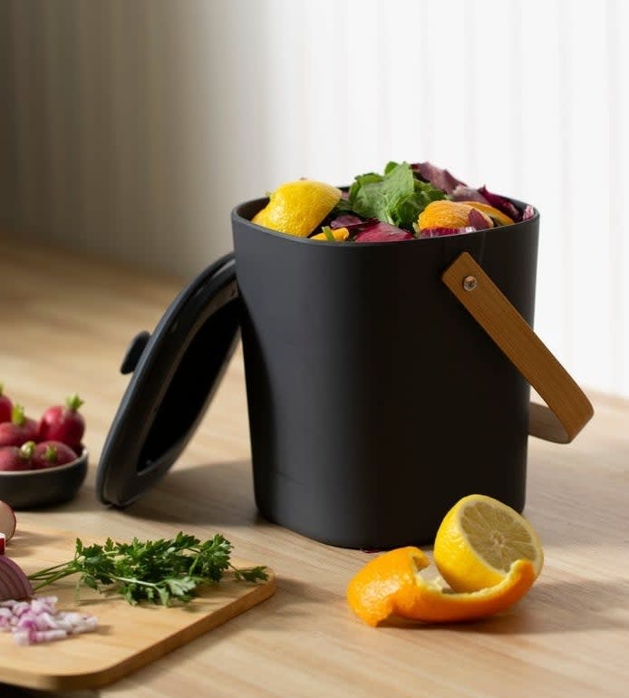 dark grey compost bin with a lid and a wood handle