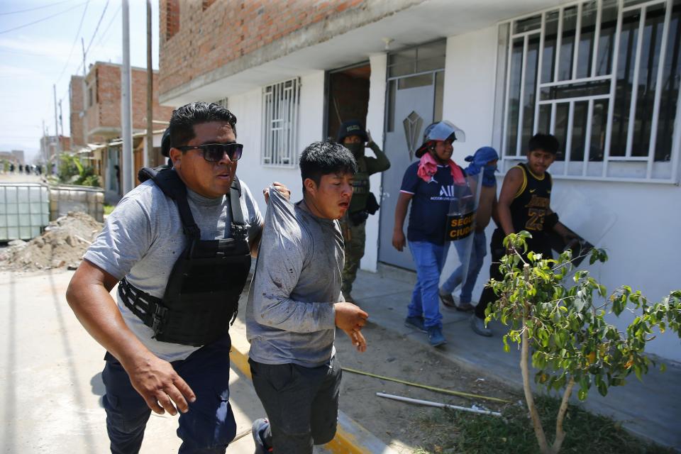 Un miembro de las fuerzas de seguridad detiene a un seguidor del destituido presidente peruano Pedro Castillo durante una protesta contra la detención de Castillo, en la autopista Panamericana Norte en Chao, Perú, el jueves 15 de diciembre de 2022. El nuevo gobierno de Perú declaró 30 días de emergencia nacional el miércoles en medio de las violentas protestas que sobrevinieron a la destitución de Castillo, que suspende derechos y libertades públicos en todo el territorio del país andino. (AP Foto/Hugo Curotto)