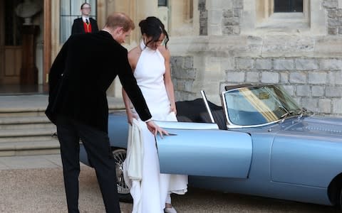 Prince Harry opens the door to the Jaguar allowing his wife to get into the passenger seat - Credit: Steve Parsons/PA