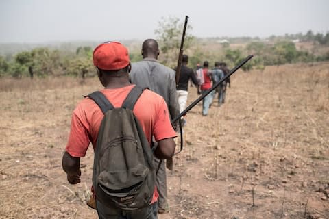 Armed men walk to the mass grave outside the village of Bakin Kogi, in Kaduna state, northwest Nigeria, that was recently attacked by suspected Fulani herdsmen - Credit: AFP