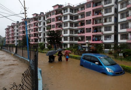 Residents walk towards dry ground from a flooded colony in Kathmandu