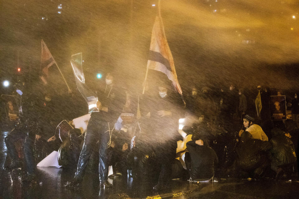 La policía israelí utiliza cañones de agua para dispersar a jóvenes de un asentamiento judío en Cisjordania durante una protesta contra la policía tras la muerte de Ahuvia Sandak en Jerusalén, durante el tercer confinamiento nacional por el coronavirus, el sábado 2 de enero de 2021. (AP Foto/Ariel Schalit)