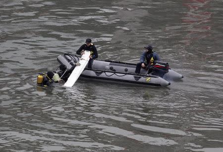 Rescue personnel retrieve an airplane part from the waters near the wreckage of TransAsia Airways plane Flight GE235 after it crash landed into a river, in New Taipei City February 5, 2015. REUTERS/Pichi Chuang