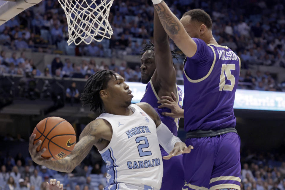 North Carolina guard Caleb Love (2) is defended by James Madison forward Alonzo Sule, center, and guard Takal Molson (15) during the first half of an NCAA college basketball game Sunday, Nov. 20, 2022, in Chapel Hill, N.C. (AP Photo/Chris Seward)