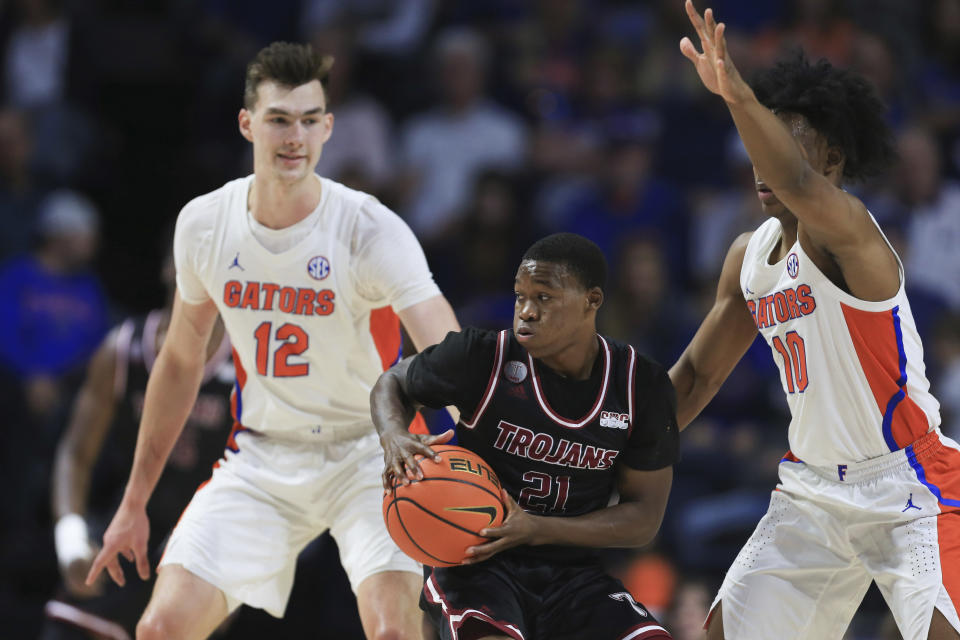 Troy guard Duke Deen (21) looks to pass the ball while guarded by Florida forward Colin Castleton (12) and guard Elijah Kennedy (10) during the first half of an NCAA college basketball game Sunday, Nov. 28, 2021, in Gainesville, Fla. (AP Photo/Matt Stamey)