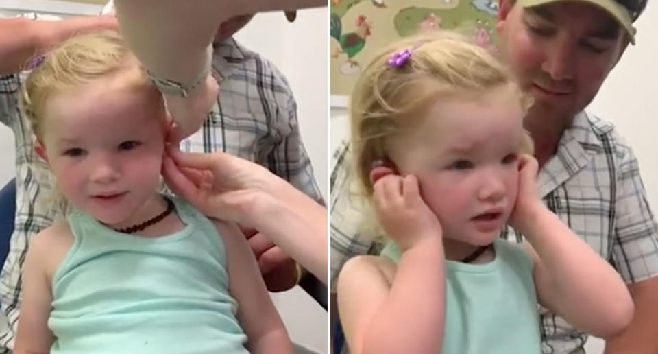 Macy Storer receives her hearing aid and hears sound fo the first time while sitting on her dad Tristan's lap.