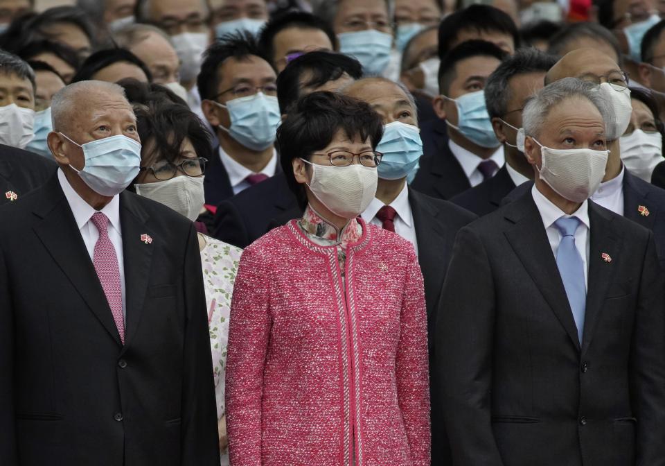 Hong Kong Chief Executive Carrie Lam, center, and former Chief Executive Tung Chee-hwa, left, and Lam's husband Lam Siu-por, right, attend the flag raising ceremony at the Golden Bauhinia Square to mark the 71st anniversary of Chinese National Day in Hong Kong Thursday, Oct. 1, 2020. (AP Photo/Vincent Yu)