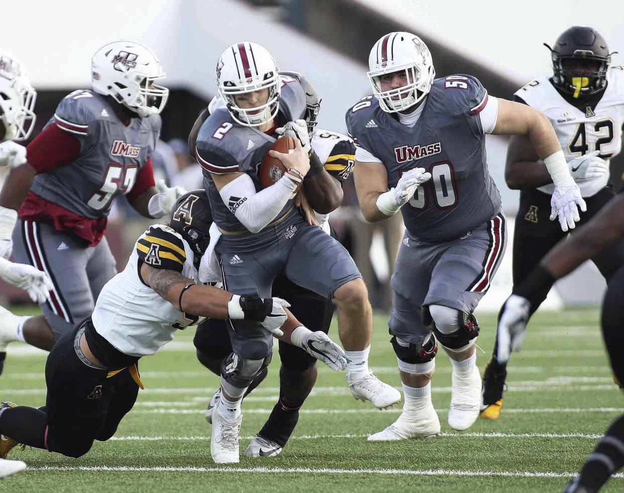 Massachusetts’s Ross Comis (2) powers the ball up field as Appalachian State’s Caleb Fuller, left, Myquon Stout attempt to bring him down during the first quarter of an NCAA college football game Saturday, Oct. 28, 2017, in Amherst, Mass. (J. Anthony Roberts/The Republican via AP)