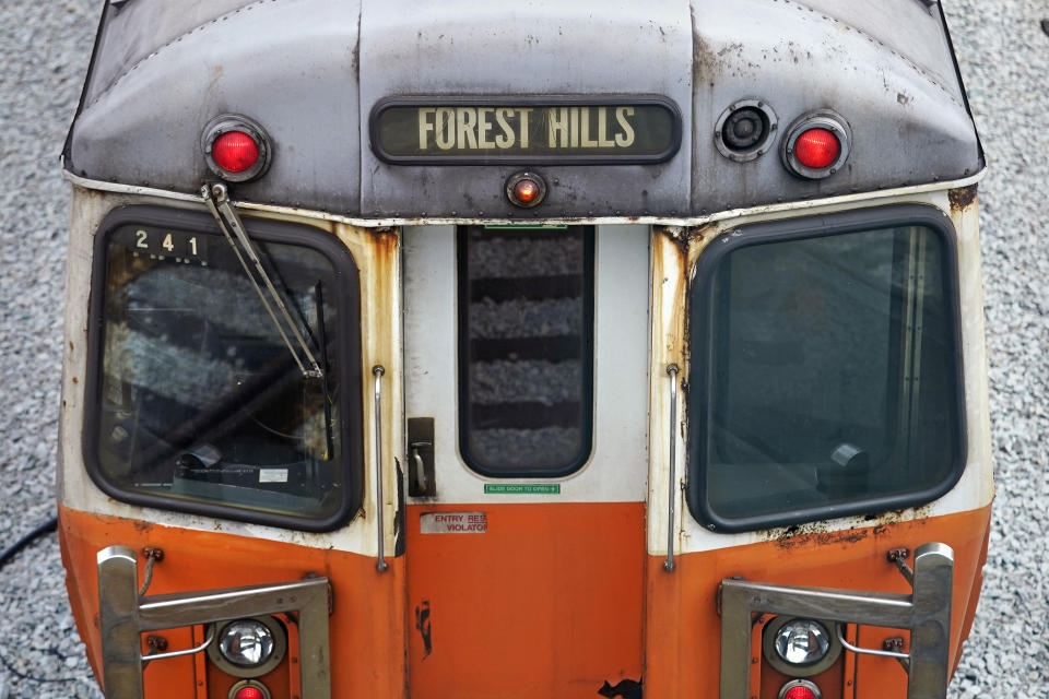 An older subway car, with spots of rust on the exterior shell, is a parked with lights on at the Orange Line's Wellington Station train yard, Wednesday, July 13, 2022, in Medford, Mass. Boston's public transit system is a mess, harried commuters and officials are increasingly looking to a Chinese-owned subway car manufacturer to account for some of the troubles. There have been fatal accidents, subway car collisions, malfunctioning elevators, and trains running on weekend schedules during rush hour. (AP Photo/Charles Krupa)