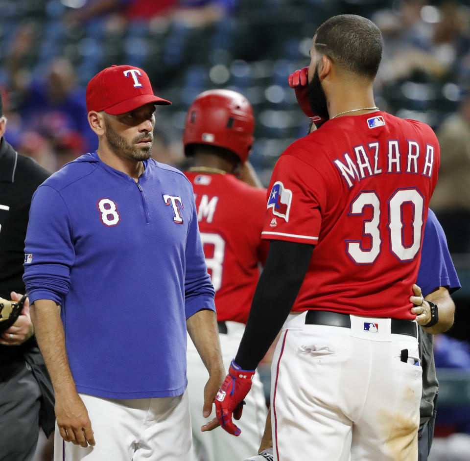 Texas Rangers manager Chris Woodward (8) checks on Nomar Mazara (30), who was hit by a pitch thrown by Cleveland Indians' Adam Cimber in the ninth inning of a baseball game in Arlington, Texas, Wednesday, June 19, 2019. The ball initially hit Mazara on the hip, then ricocheted and also hit him on the face. Mazara remained in the game. (AP Photo/Tony Gutierrez)