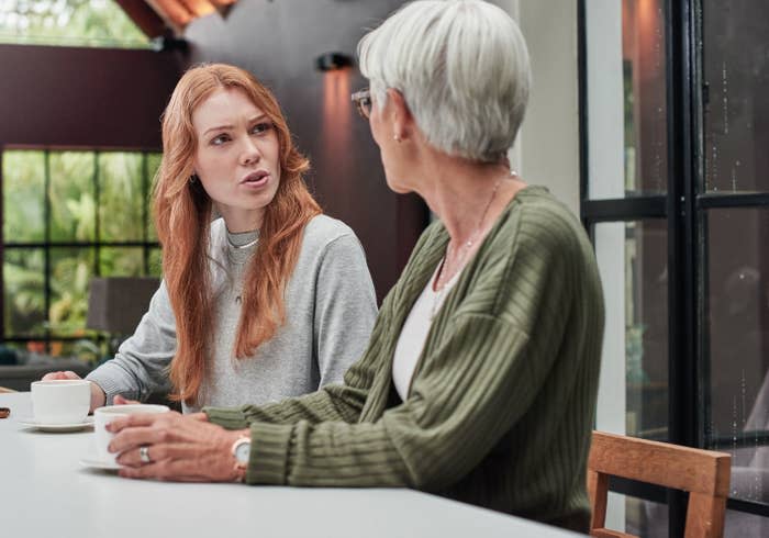 Two women conversing at a table with coffee cups