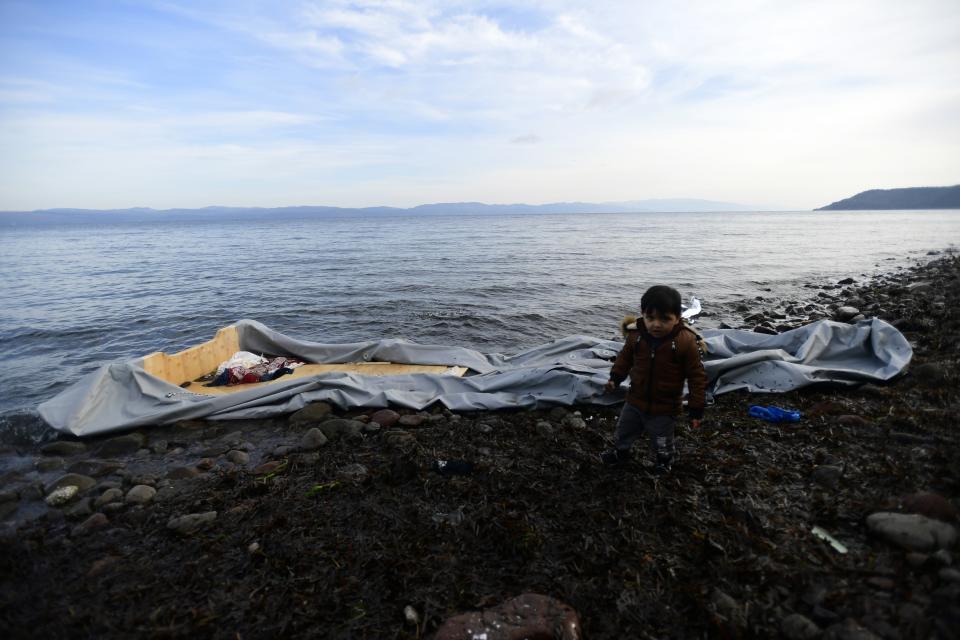 A boy stands next to a dinghy at the village of Skala Sikaminias, on the Greek island of Lesbos, after crossing with other migrants the Aegean sea from Turkey, Sunday, March 1, 2020. Turkey's President Recep Tayyip Erdogan said his country's borders with Europe were open Saturday, making good on a longstanding threat to let refugees into the continent as thousands of migrants gathered at the frontier with Greece. (AP Photo/Michael Varaklas)