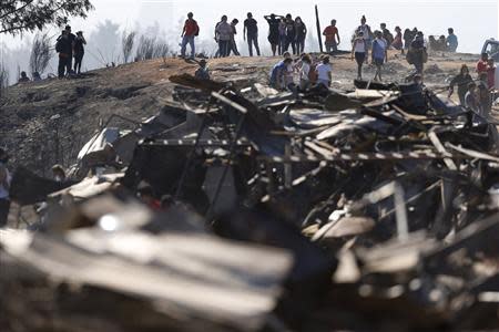 Residents remove debris from their burned houses after a fire burned several neighbourhoods in the hills in Valparaiso city, northwest of Santiago April 14, 2014. REUTERS/Ivan Alvarado