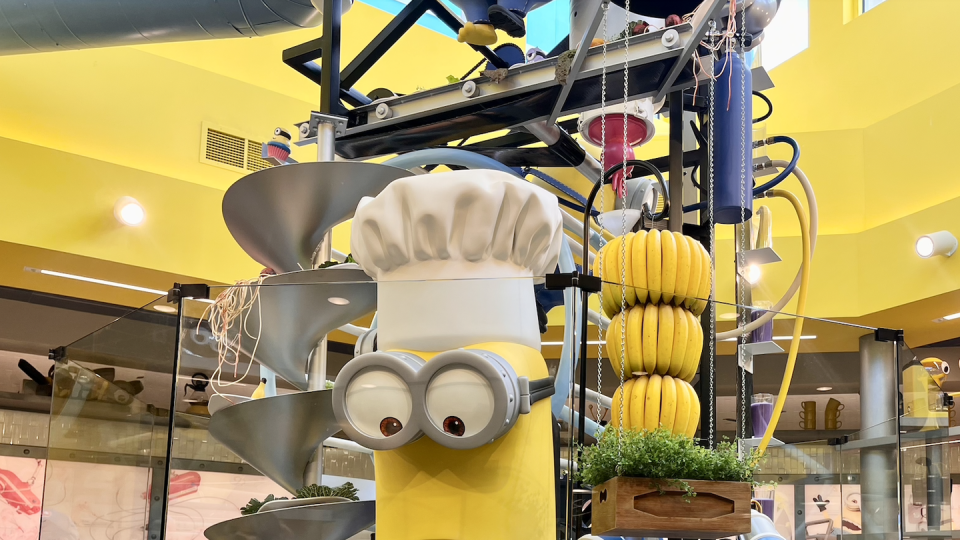 universal studios minion land cafe, statues of minion characters with plates of food in front