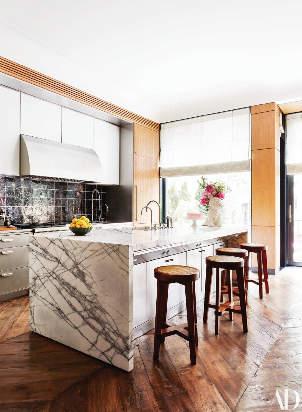 The kitchen features a custom hood and oak millwork by Ingrao. The backsplash is made of tiles by Exquisite surfaces; vintage Pierre Jeanneret stools.