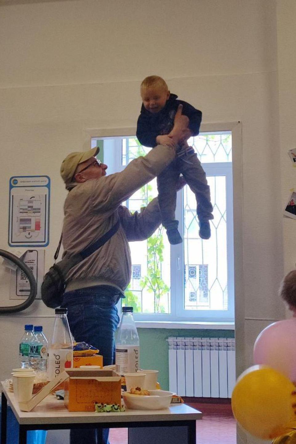 A Rescue driver throws Matviy in the air, the toddler laughing in delight (Andrii Semenko)