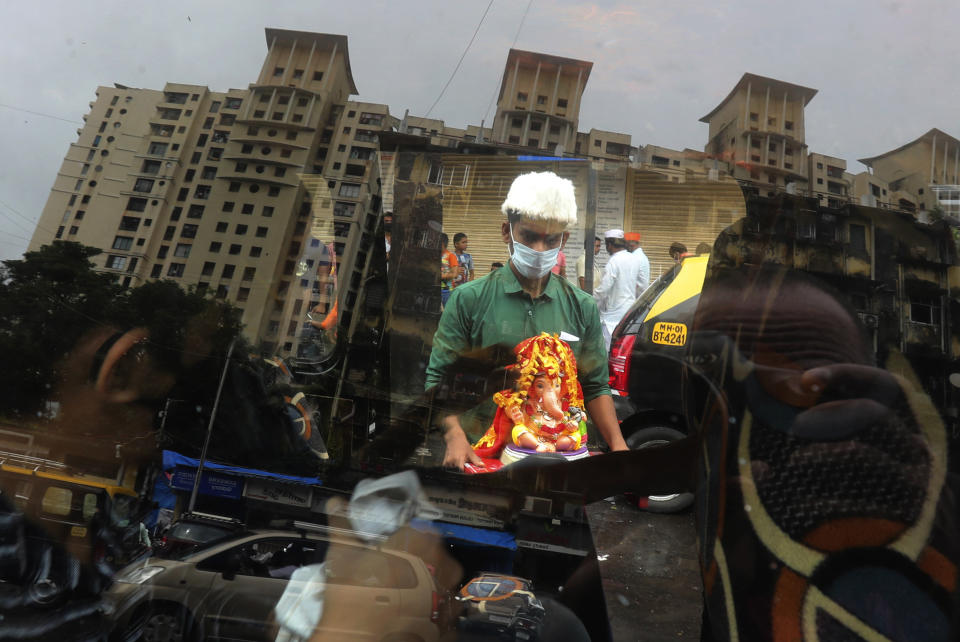 A devotee wearing a mask carries home an idol of elephant-headed Hindu god Ganesha for worship during Ganesh Chaturthi festival celebrations in Mumbai, India, Saturday, Aug. 22, 2020. The 10-day long Ganesh festival began Thursday and ends with the immersion of Ganesha idols in water bodies on the final day. (AP Photo/Rafiq Maqbool)