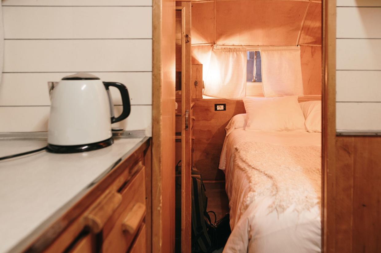 Inside view of a vintage motor home with a small kitchen and a bed