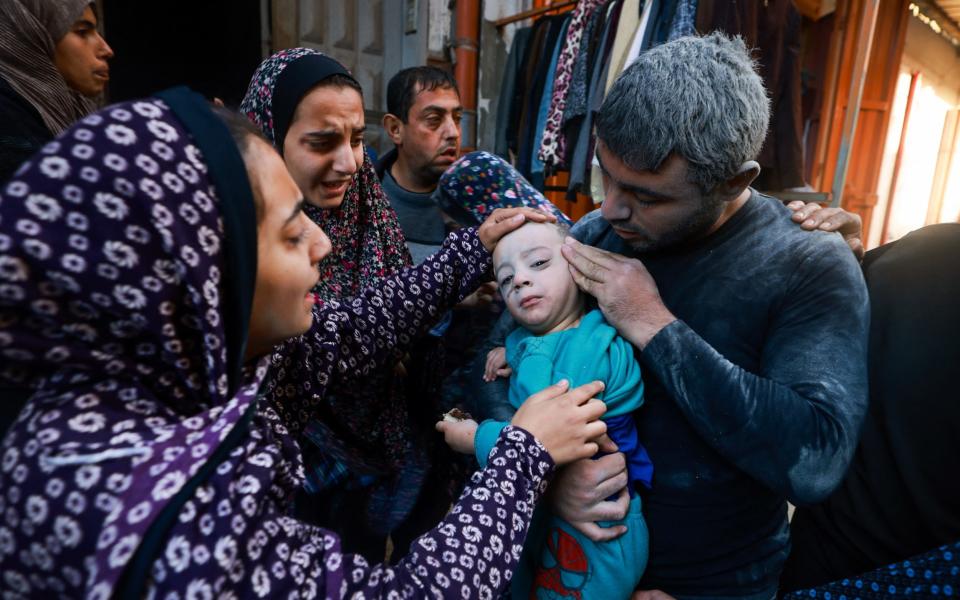 A Palestinian man checks the injuries of a child as they flee