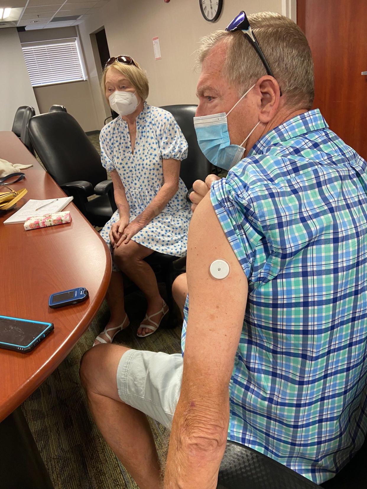 Jerry Branham demonstrates how inconspicuous the sensor for his glucose monitoring system is. With him in the conference room is his wife, Debbie.