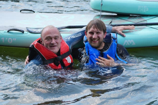 Sir Ed Davey (left) with Freddie van Mierlo in a river next to a paddle board