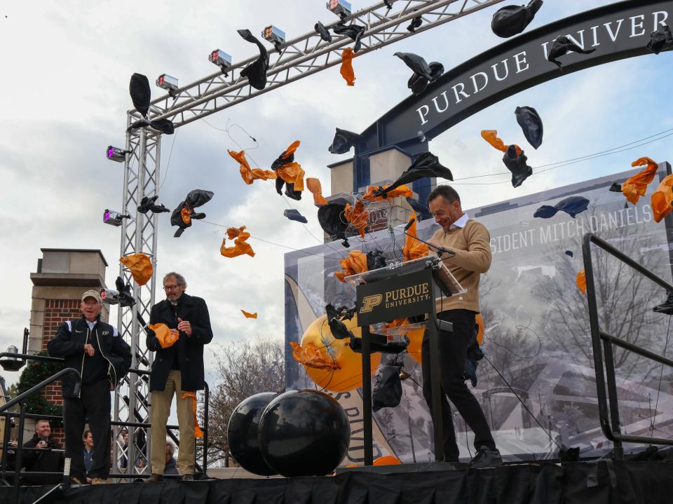 Purdue University President Mitch Daniels, West Lafayette Mayor John Dennis and Michael Berghoff, chairman of the Purdue University board of trustees, jump after being scared by popping ballons during MitchFest, on Friday, December 2, 2022, in West Lafayette, Ind.