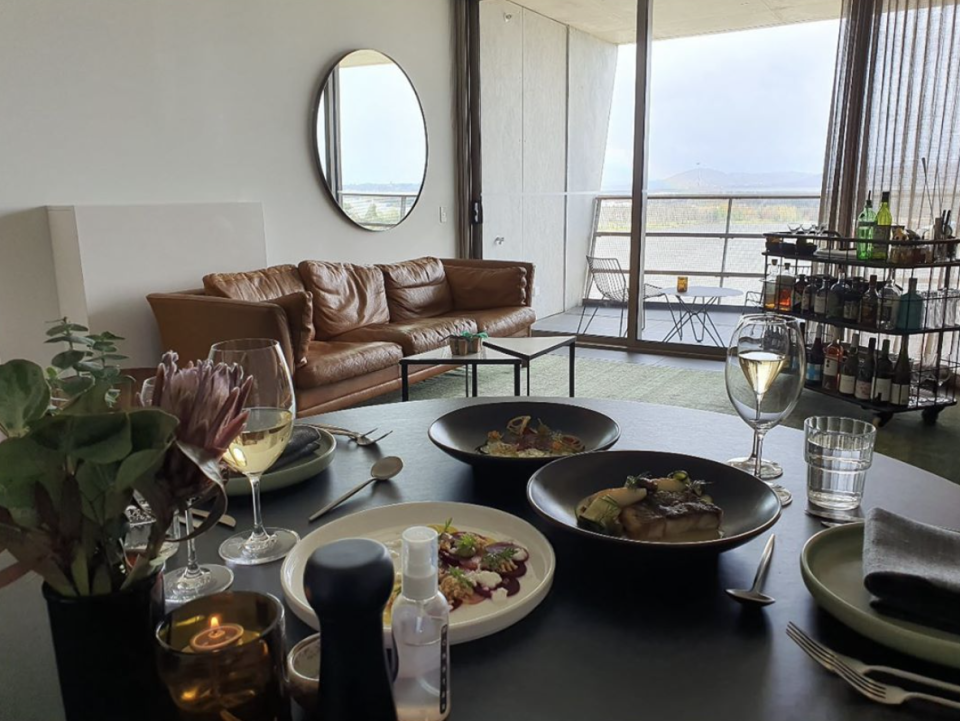 Inside a hotel room at the Ovolo Nishi in Canberra a dining table is set with plates of food and wine glasses