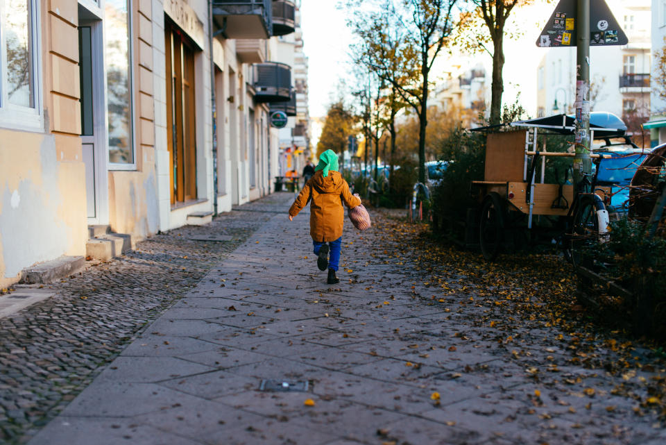 Young boy running home with a bag