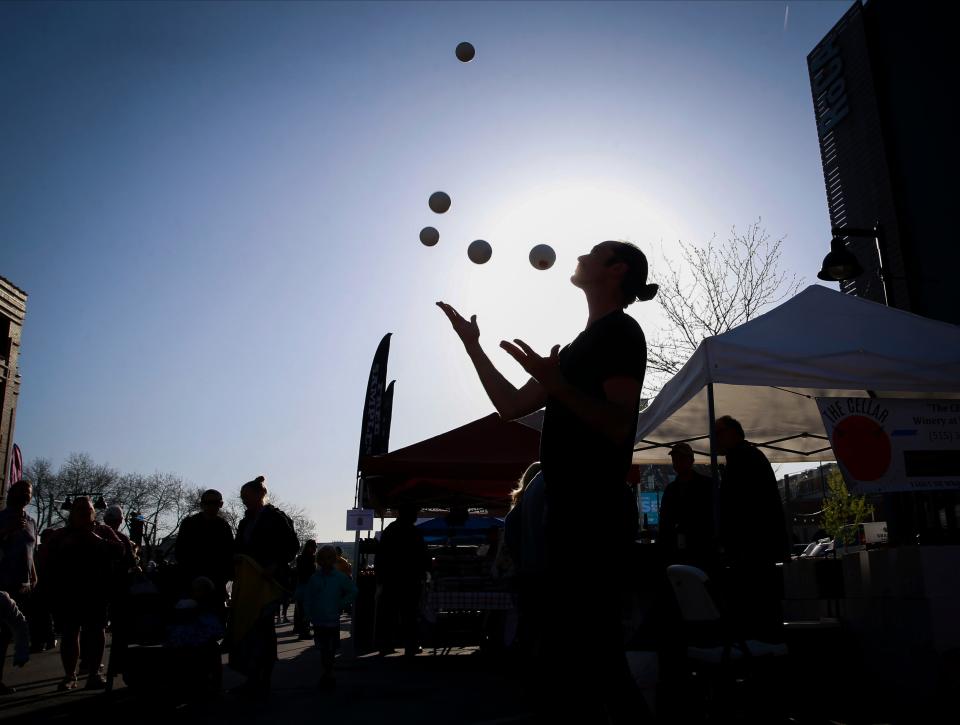 Juggler Luther Bangert of Iowa City performs as shoppers make their way along Court Avenue during the opening day of the 2022 Downtown Des Moines Farmers' Market.