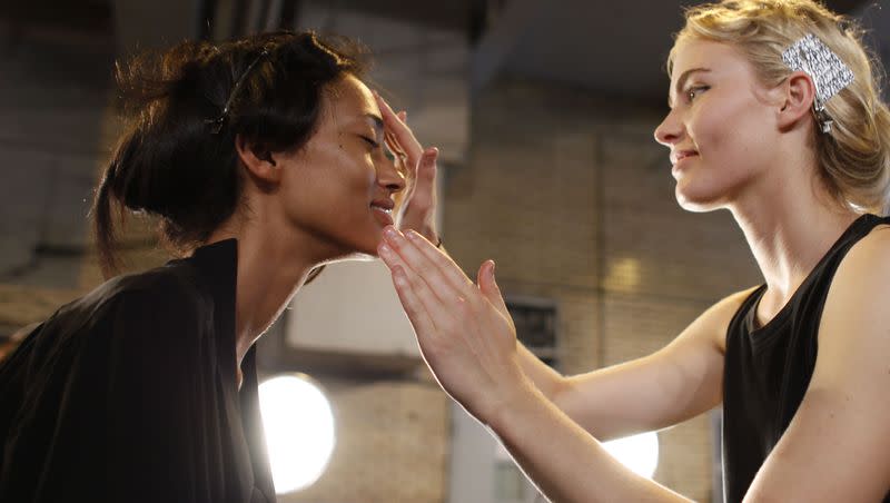 A model has skin care product applied to her face by another model as they wait to be made up backstage during Fashion Week, Saturday, Sept. 8, 2012, in New York. 