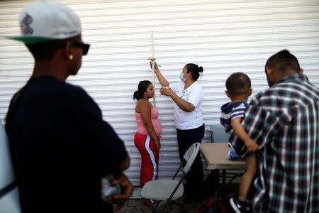 A Central American migrant, moving in a caravan through Mexico and traveling to request asylum in U.S, checks her health status as she arrives to Mexicali, Baja California state, Mexico April 25, 2018. REUTERS/Edgard Garrido