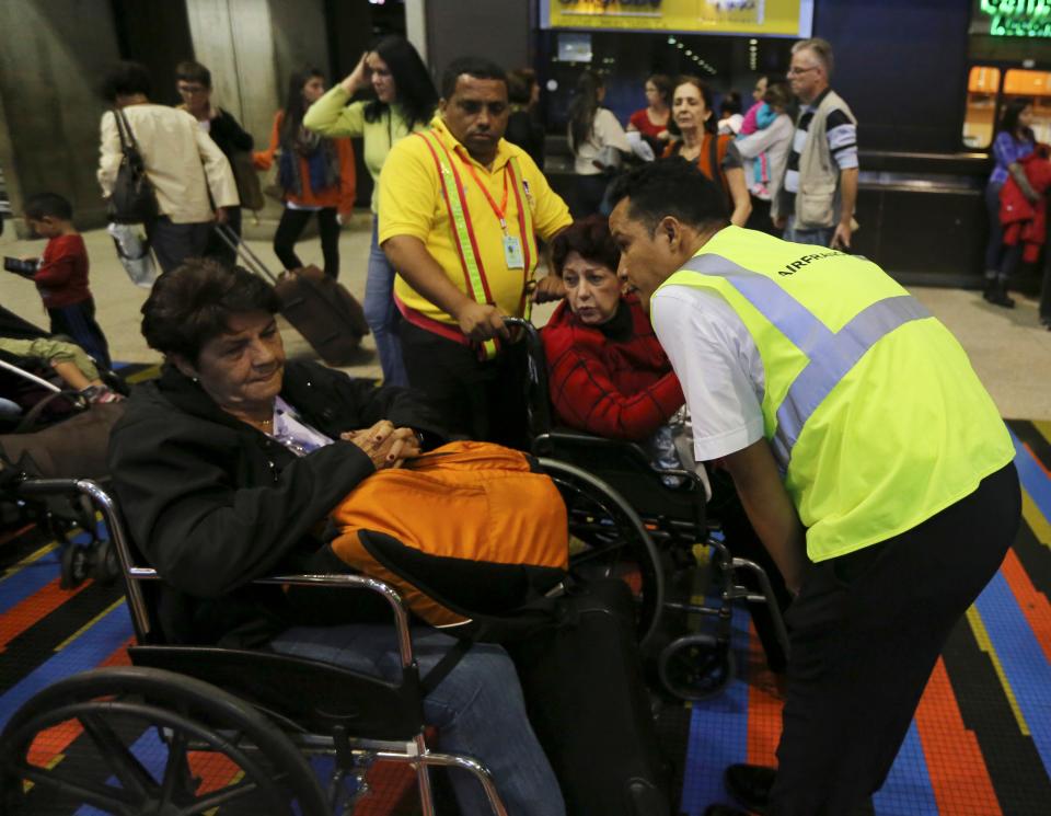 A employee of Air France speaks with some passengers in front of the Air France desk after their flight to Paris was canceled at Simon Bolivar Airport in Maiquetia near Caracas, Venezuela, Sunday, Dec. 15, 2013. Venezuelan bomb experts are inspecting a grounded Air France flight after being tipped off by French authorities that a terrorist group may be planning to detonate an explosive device in midair. Venezuelan Interior Minister Miguel Rodriguez Torres told state TV that a team of more than 60 technicians are performing an exhaustive search of the aircraft that will take several hours before the flight can be rescheduled.(AP Photo/Fernando Llano)