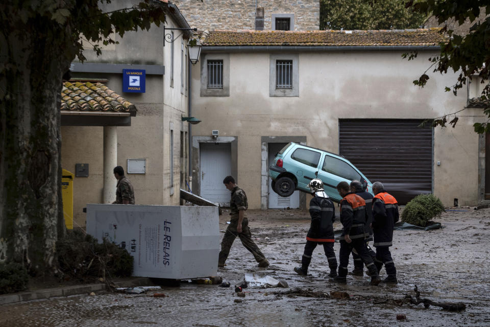 Rescue workers and soldiers walk in the town of Villegailhenc, southern France, after flash floods Monday, Oct.15, 2018. Flash floods tore through towns in southwest France, turning streams into raging torrents that authorities said killed several people and seriously injured at least five others. (AP Photo/Fred Lancelot)