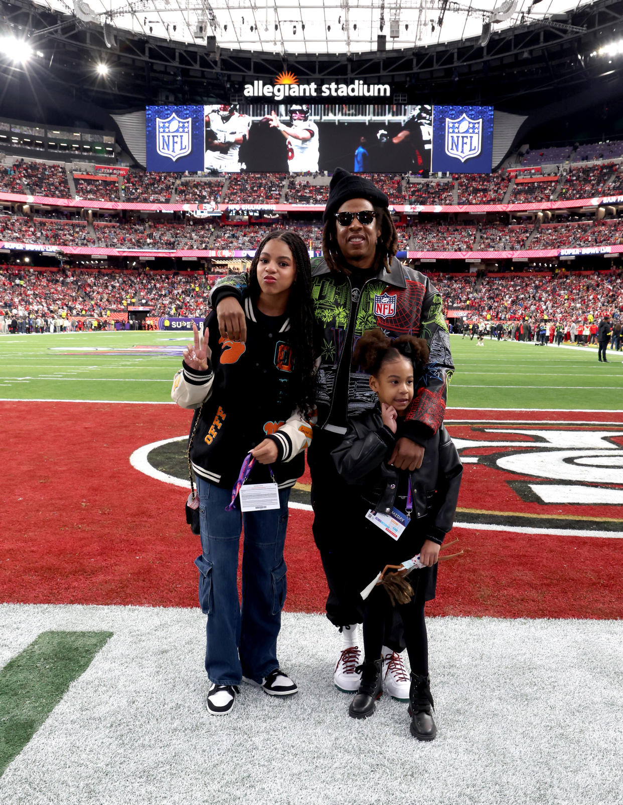 Blue Ivy Carter and Rumi Carter with their dad, Jay-Z, pose together on the field at the Super Bowl.