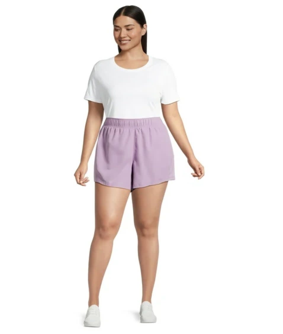 Model wearing white T-shirt and lilac shorts, paired with white sneakers