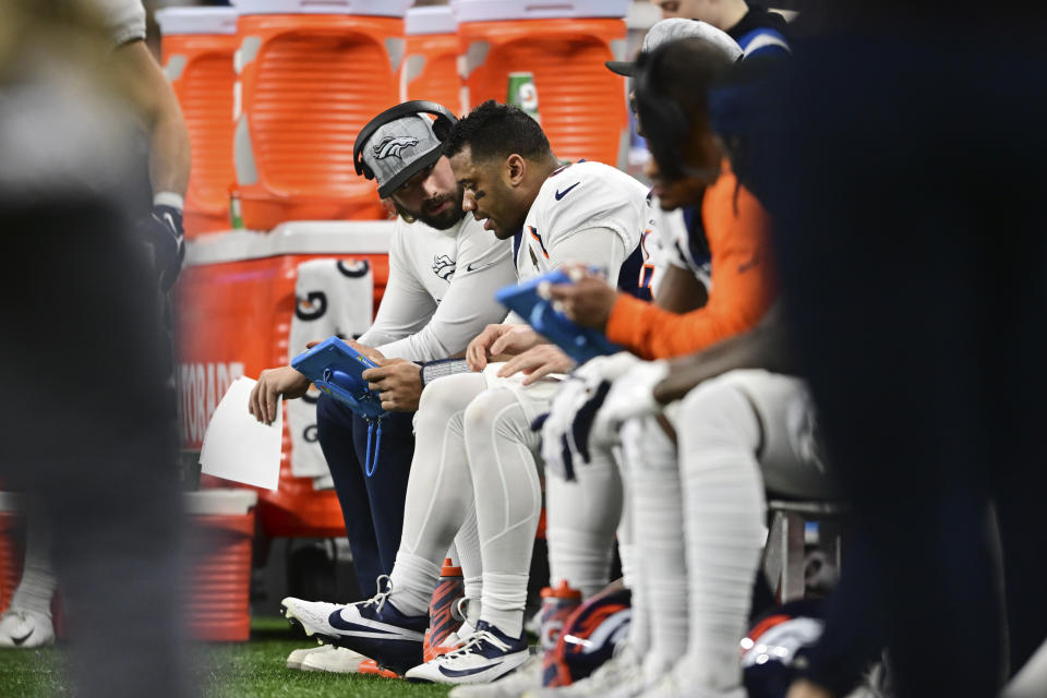 Denver Broncos quarterbacks coach Davis Webb talks with quarterback Russell Wilson during the first half of an NFL football game against the Detroit Lions, Saturday, Dec. 16, 2023, in Detroit. (AP Photo/David Dermer)