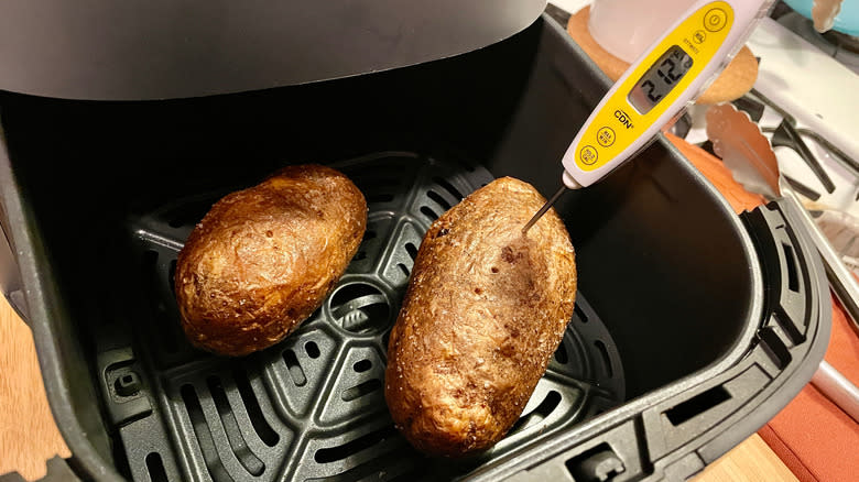 An instant read digital thermometer checking the internal temperature of potatoes in an air fryer