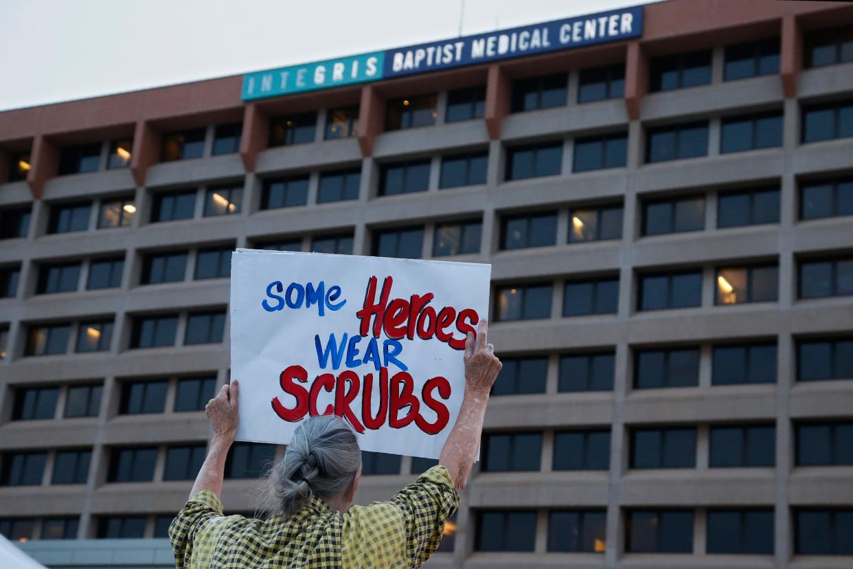 A woman holds a sign in the parking lot of Integris Baptist Medical Center during a "Headlights for Hope" event in Oklahoma City, in a show of support for healthcare workers amid the COVID-19 outbreak.