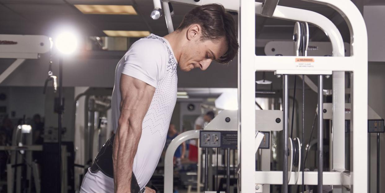 one young man, 20 years old, side view, gym indoors, dip exercise, dipping stand station