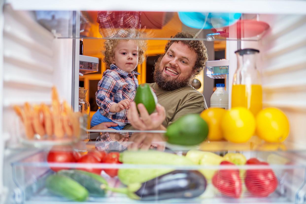 Father and son taking produce from back of fridge