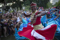 A man dances during the "Tambores de Olokun" street party in Rio de Janeiro, Brazil, Saturday, Feb. 15, 2020. Thousands have started attending the popular street parties ahead of the world's famous carnival festival that begins on Feb 21. (AP Photo/Silvia Izquierdo)