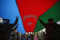 Azerbaijani soldiers carry a huge national flag as they celebrate the transfer of the Lachin region to Azerbaijan's control, as part of a peace deal that required Armenian forces to cede the Azerbaijani territories they held outside Nagorno-Karabakh, in Aghjabadi, Azerbaijan, Tuesday, Dec. 1, 2020. Azerbaijan has completed the return of territory ceded by Armenia under a Russia-brokered peace deal that ended six weeks of fierce fighting over Nagorno-Karabakh. Azerbaijani President Ilham Aliyev hailed the restoration of control over the Lachin region and other territories as a historic achievement. (AP Photo/Emrah Gurel)