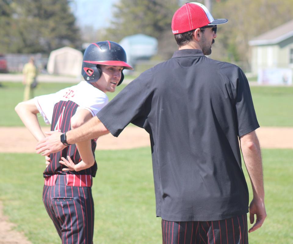 Onaway assistant coach Trevor Wregglesworth congratulates senior Cole Selke (4) on a successful steal during a baseball game at Pellston last week.