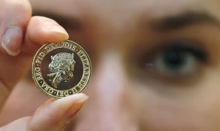 A gallery assistant poses with a 2-pound coin with the new portrait of Britain's Queen Elizabeth following it's unveiling at the National Portrait Gallery in London, March 2, 2015. REUTERS/Suzanne Plunkett