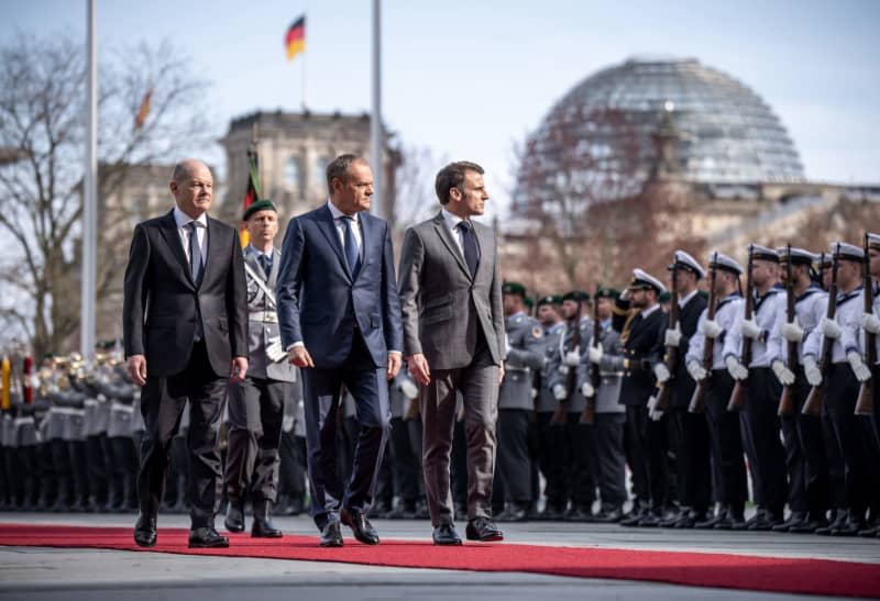 (L-R) German Chancellor Olaf Scholz, Polish Prime Minister Donald Tusk and French President Emmanuel Macron inspect a military honour guard at the Chancellery. The so-called Weimar Triangle top level meeting is taking place against the backdrop of massive Franco-German differences over Ukraine policy. Michael Kappeler/dpa