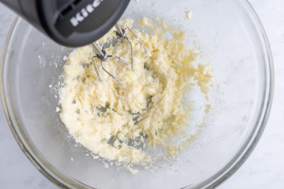 Hand mixer creaming butter and sugar in glass bowl