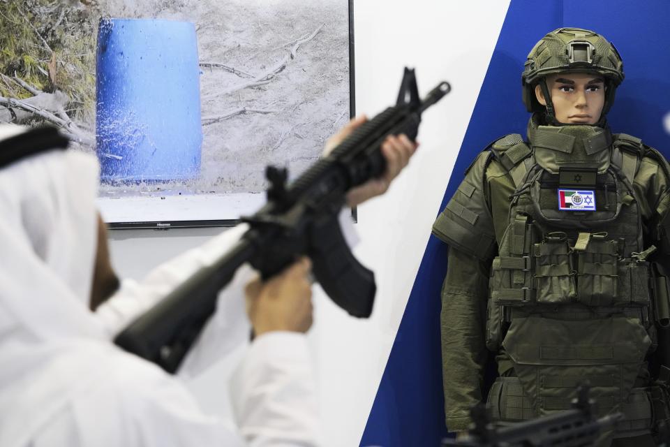 An Emirati examines an Israeli rifle at the International Defense Exhibition and Conference in Abu Dhabi, United Arab Emirates, Monday, Feb. 20, 2023. Just outside of Abu Dhabi's biennial arms fair in a large tent, Russia offered weapons for sale Monday ranging from Kalashnikov assault rifles to missile systems despite facing sanctions from the West over its war on Ukraine. (AP Photo/Jon Gambrell)