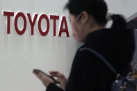 FILE - In this Jan. 30, 2020, file photo, a visitor stands by the logo of Toyota Motor Corp. at its showroom in Tokyo. Japan's top automaker Toyota is seeing more cases among employees as coronavirus infections climb in Japan, partly because of a gradual increase in testing. Toyota Motor Corp. said Monday, Aug. 17, 20 employees were confirmed with COVID-19 so far, seven of them this month. (AP Photo/Eugene Hoshiko, File)